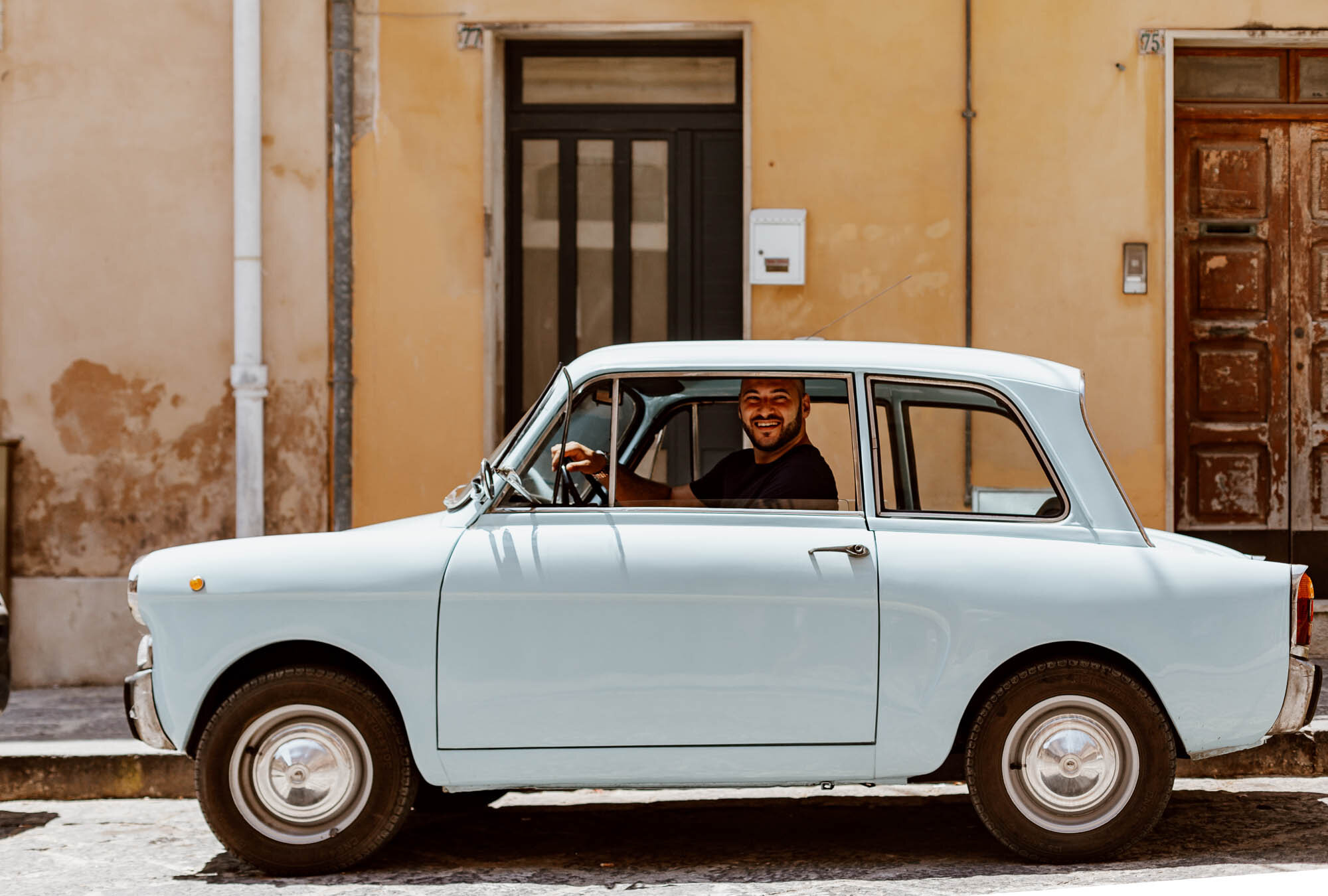 Smiling Italian man in vintage car in Noto